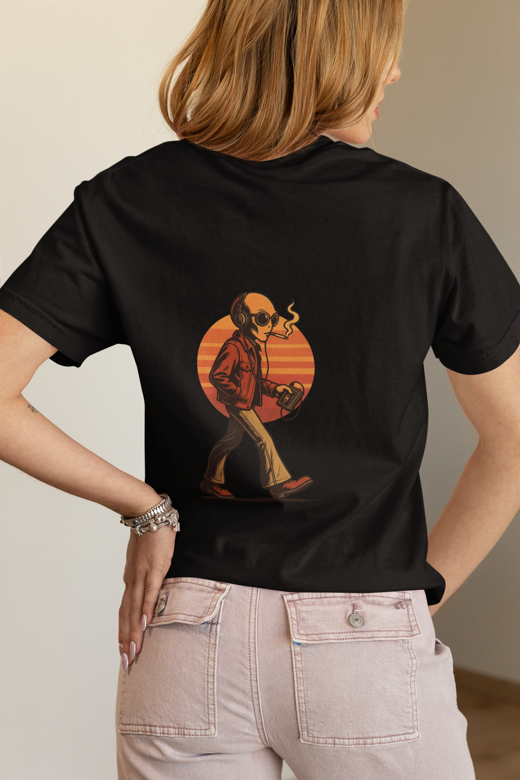Woman wearing a black oversized t-shirt with back-printed smoking alien graphic in front of a soft indoor background