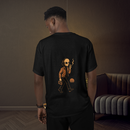 Black unisex t-shirt featuring a back-printed graphic of a smoking alien with headphones and a cassette player, standing indoors with moody ambient lighting.